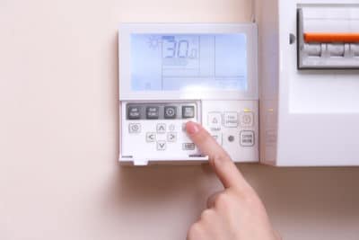 Person using smart thermostat on wall