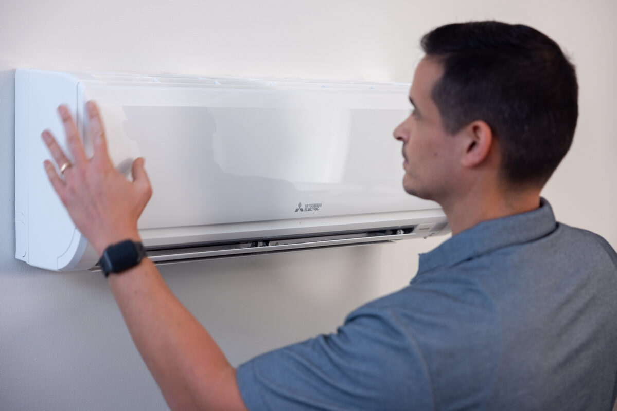 Technician adjusting wall-mounted thermostat controls